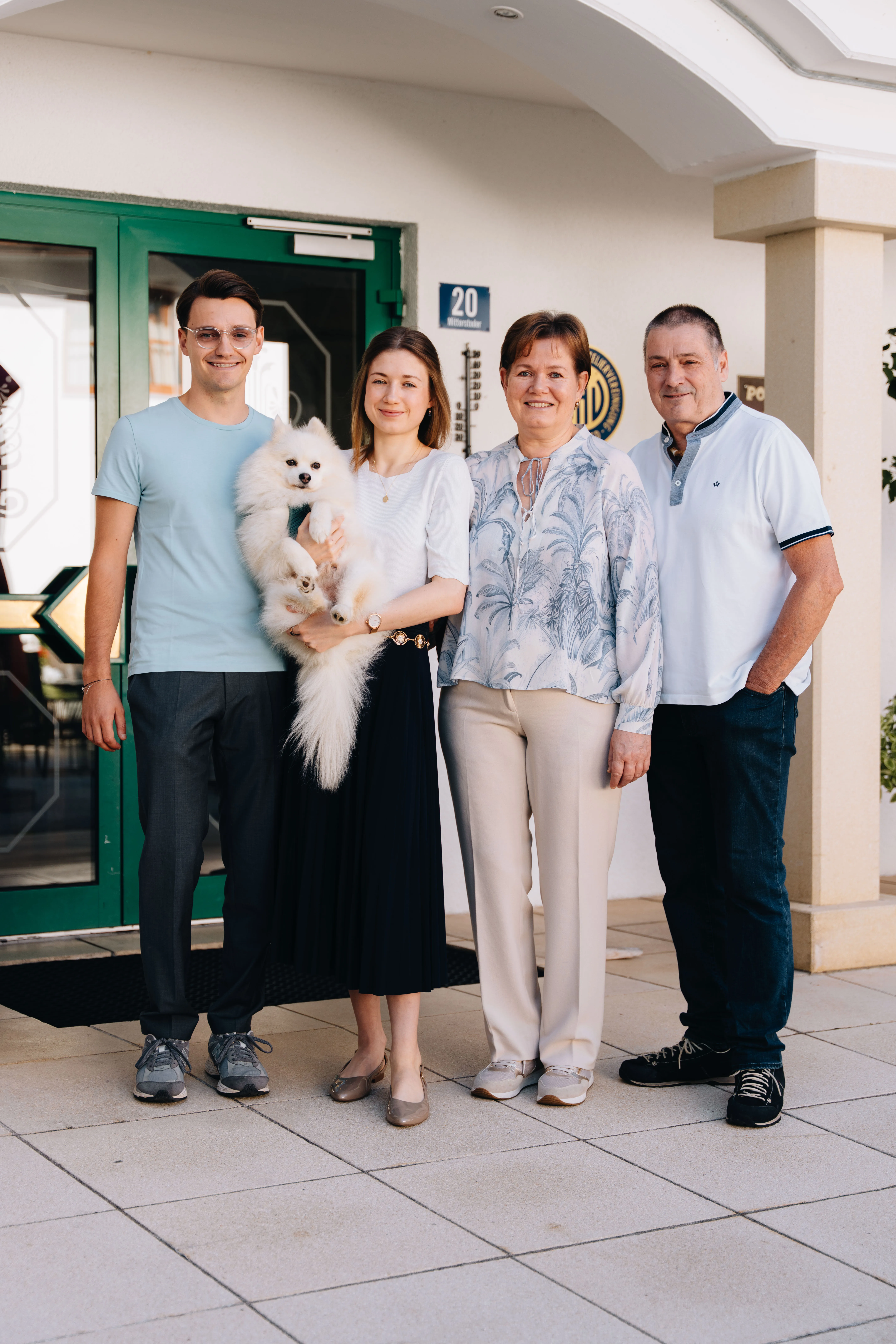 © Hartwig Winkler Familie Kniewasser vor dem grünen Hauseingang des Poppengut, eine der Töchter hält einen kleinen weißen Hund im Arm