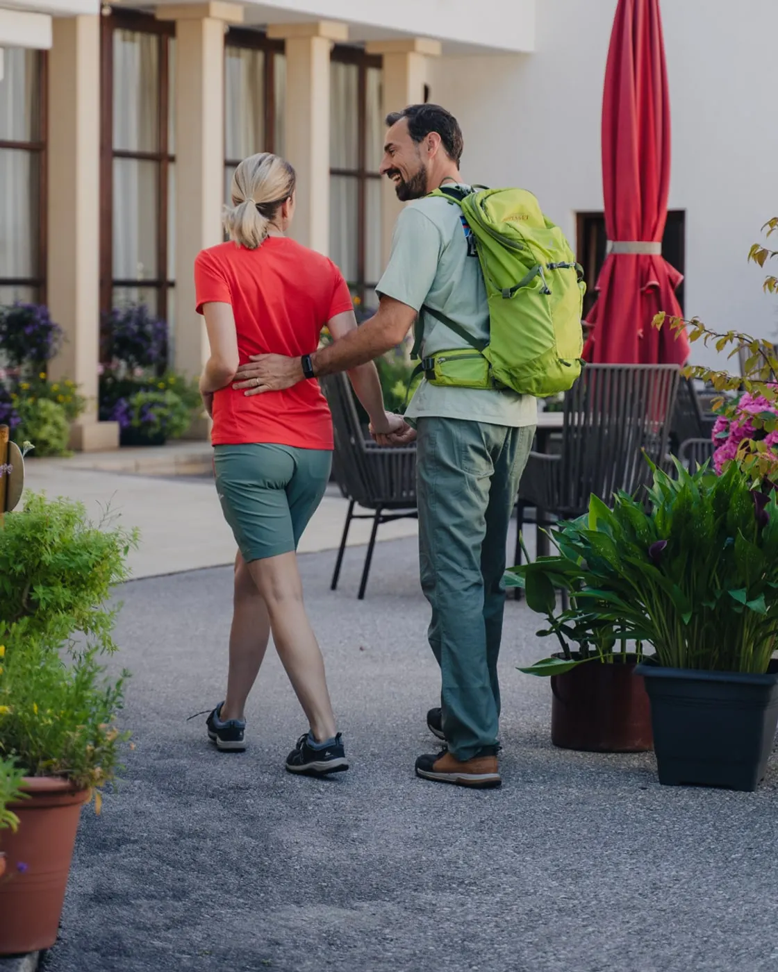 © Sarah Kreutzhuber Wanderpaar auf dem Weg vor der Terrasse des Poppengut, er legt ihr den Arm um die Hüfte und lacht sie an