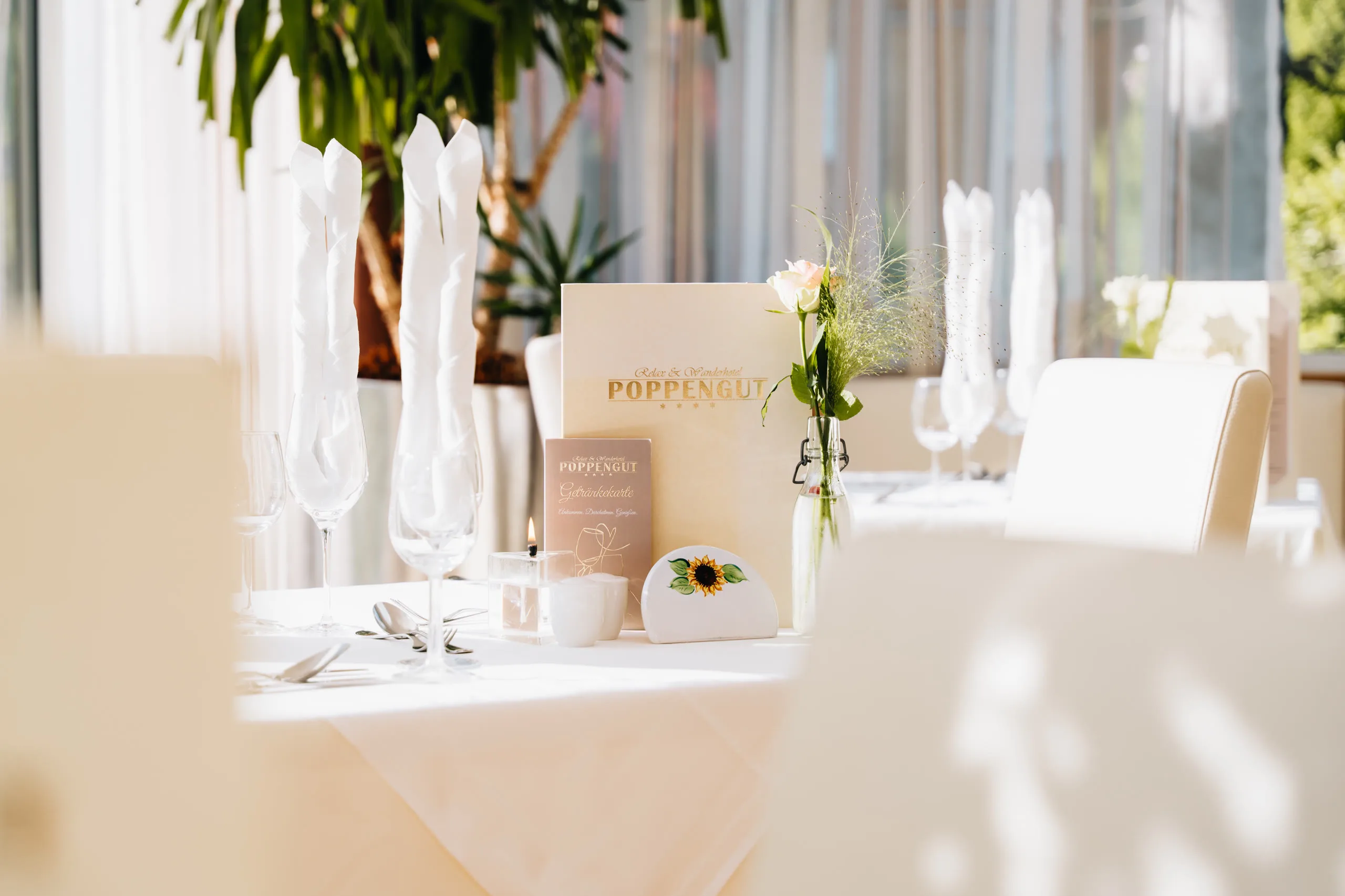 © Hartwig Winkler Festlich gedeckter Tisch im Restaurant, Speise- und Getränkekarte des Poppengut, Kerze und eine Rose in der Vase